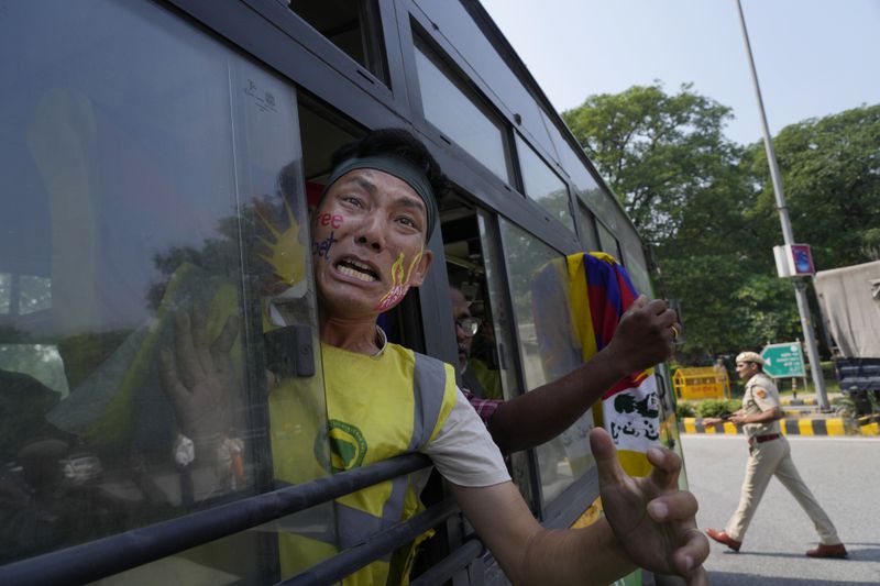 An exile Tibetan shouts slogans against the human rights situation in Tibet from a police vehicle as he is detained during a protest to coincide China marking its 75th year of Communist Party rule, outside Chinese embassy, in New Delhi, India, Tuesday, Oct. 1, 2024. (AP Photo/Manish Swarup)