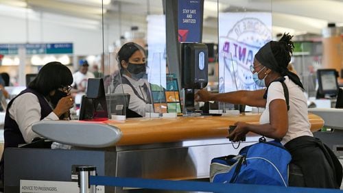 July 22, 2020 Atlanta - Delta Air Lines employees work behind plexiglass screens as they check-in passengers at Hartsfield-Jackson International Airport on Wednesday, July 22, 2020. (Hyosub Shin / Hyosub.Shin@ajc.com)