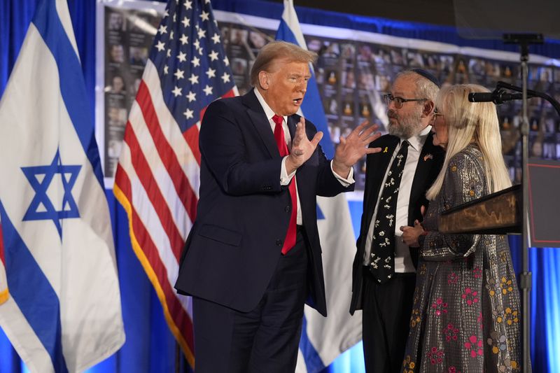 Republican presidential nominee former President Donald Trump talks with Miriam Adelson and Rabbi Yeshuda Kaploun at an event marking one year since the Oct. 7 Hamas attack on Israel, Monday, Oct. 7, 2024, in Miami. (AP Photo/Alex Brandon)