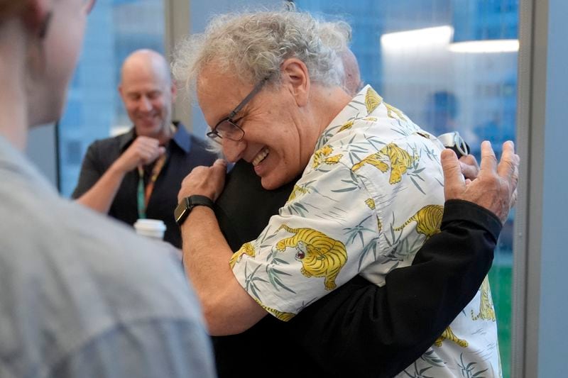 Victor Ambros, 2024 Nobel Prize winner in physiology or medicine, and professor of natural science at the University of Massachusetts Medical School, right, hugs collegue Allan Jacobson, at the school, in Worcester, Mass. Monday, Oct. 7, 2024. (AP Photo/Steven Senne)