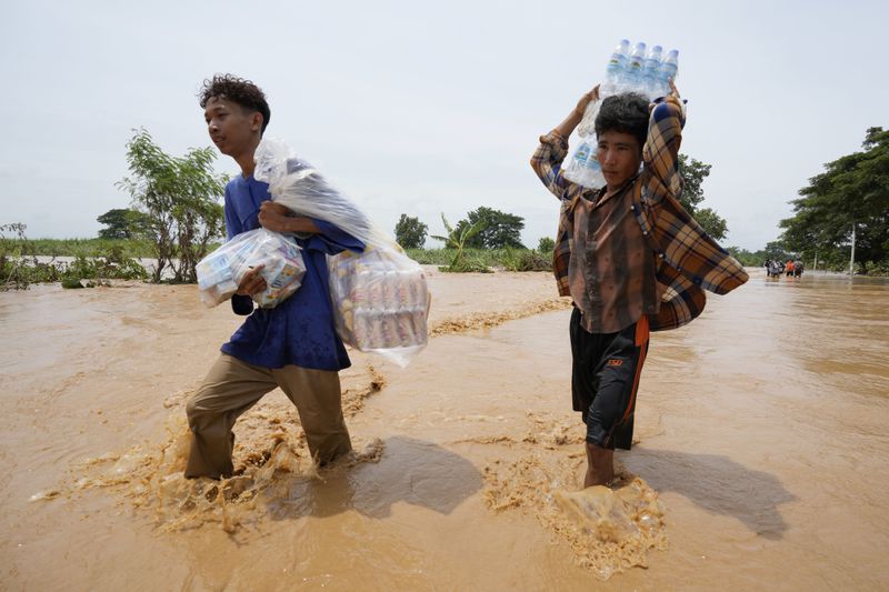 Local residents carrying food wade through a flooded road in Naypyitaw, Myanmar, Saturday, Sept. 14, 2024. (AP Photo/Aung Shine Oo)