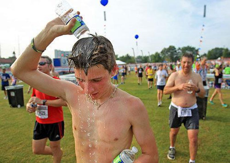 Chris Draper, 15, of Roswell, dumps water on his head to cool him off after he finished his first AJC Peachtree Road Race.