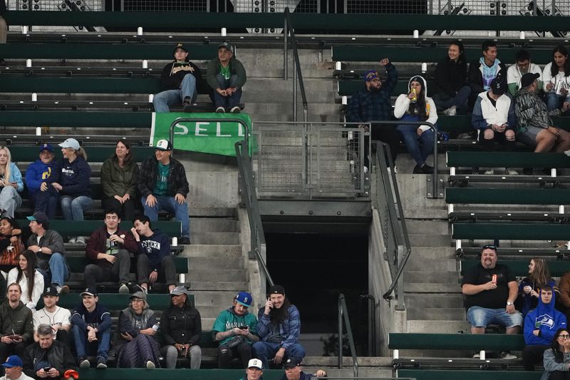 Fans sit near a "sell" flag during the eighth inning of a baseball game between the Seattle Mariners and the Oakland Athletics, Friday, Sept. 27, 2024, in Seattle. (AP Photo/Lindsey Wasson)