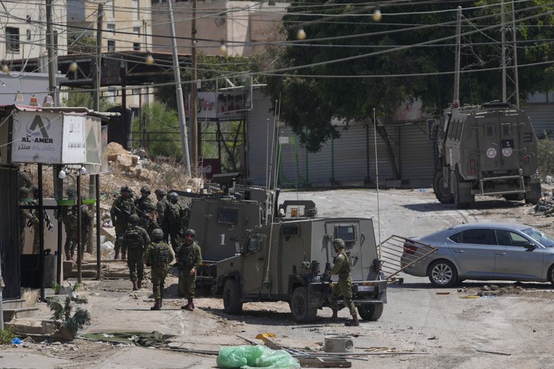 Members of Israeli forces patrol a street during a military operation in the West Bank refugee camp of Al-Faraa, Wednesday, Aug. 28, 2024. (AP Photo/Nasser Nasser)