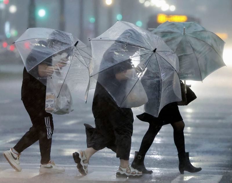 People holding umbrella, struggle with the heavy rain as a typhoon is approaching in Kagoshima, western Japan, Wednesday, Aug. 28, 2024, (Hidetaka Komukai/Kyodo News via AP)