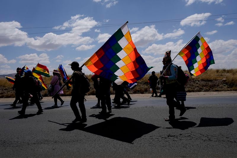 Demonstrators carrying wiphala flags march to the capital from Caracollo, Oruro, Bolivia, led by former President Evo Morales as part of a political dispute with current President Luis Arce and to protest his handling of the economy, Tuesday, Sept. 17, 2024. (AP Photo/Juan Karita)