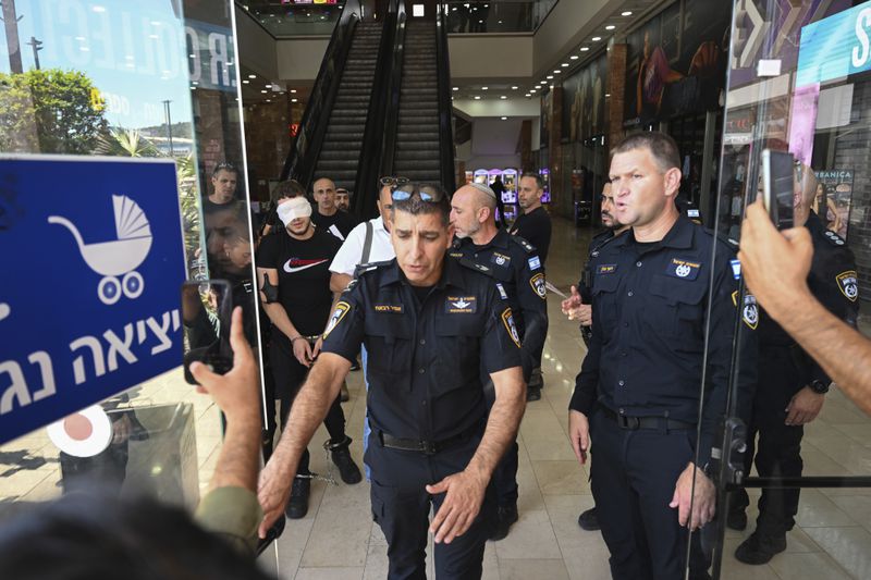 Israeli police arrest a man outside a shopping mall following a stabbing attack in Karmiel, northern Israel, Wednesday, July 3, 2024. One person was killed and one person wounded in a stabbing attack at a shopping mall in what Israeli police say was a terrorist attack. The police say the assailant was killed. They did not provide the name or nationality of the attacker. (AP Photo/Rami Shlush)