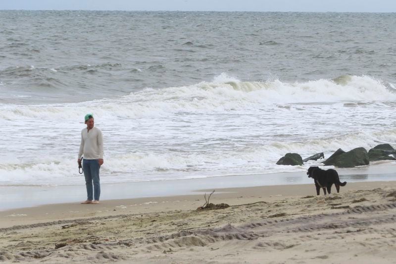 A man walks his dog on the beach, Sept. 30, 2024, in Sea Girt, N.J., the location where a future power cable from an offshore wind farms is projected to come ashore. (AP Photo/Wayne Parry)