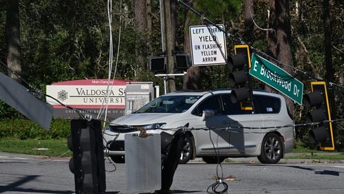 A car drives by fallen traffic signals and wires near Valdosta State University, Saturday, September 28, 2024, in Valdosta. The devastation in Valdosta was extensive after the South Georgia city was battered with hurricane-force winds on Helene’s path across the state. Damaging Helene has swept through Georgia, leading to at least 15 deaths. All 159 counties are now assessing the devastation and working to rebuild, even as serious flooding risks linger. (Hyosub Shin / AJC)