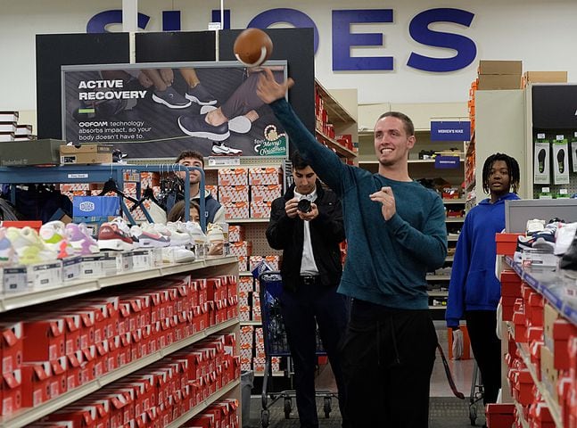 UGA quarterback Carson Beck tosses a football to a Boys and Girls club member in the shoe aisle. Carson Beck was on site at an Athens Academy store Sunday December 17, 2023, to give out gift cards to lucky members of area Boys and Girls Clubs. Academy contributed $200 for each child and he kicked in $135 more of his own money to help families out. 
credit: Nell Carroll for the AJC
