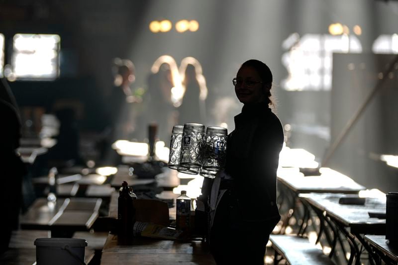 A waitress prepares beer mugs in the Augustiner marquee for the start of the 189th 'Oktoberfest' beer festival in Munich, Germany, Saturday morning, Sept. 21, 2024. (AP Photo/Matthias Schrader)