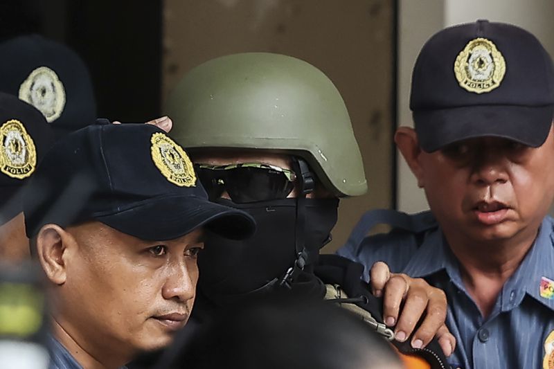 Apollo Carreon Quiboloy, wearing a helmet and flak jacket, a Filipino preacher charged with human trafficking, leaves the Pasig Regional Trial Court in Pasig City, Philippines, Friday, Sept. 13, 2024. (AP Photo/Gerard Carreon)