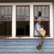 Ben Phillips scoops mud out a window of his house left in the wake of Hurricane Helene, Tuesday, Oct. 1, 2024, in Marshall, N.C. (AP Photo/Jeff Roberson)