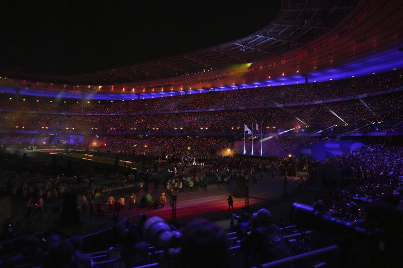 The Paralympic flag flutters next to the French flag during the closing ceremony of the 2024 Paralympics, Sunday, Sept. 8, 2024, in Paris, France. (AP Photo/Thibault Camus)