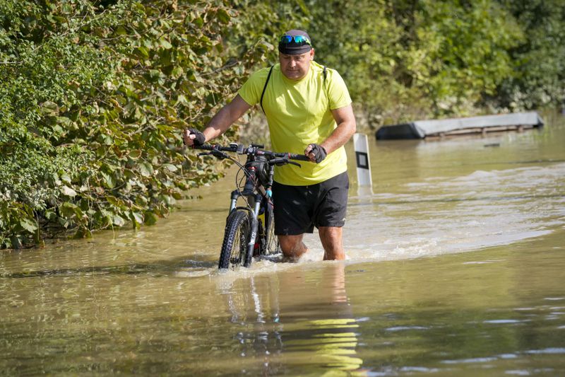 A cyclist pushes his bicycle through a flooded street in Bohumin, Czech Republic, Tuesday, Sept. 17, 2024. (AP Photo/Darko Bandic)