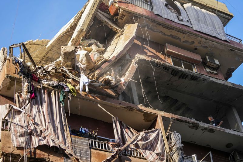 Residents check a partially destroyed building at the site of an Israeli airstrike in Beirut's southern suburbs, Tuesday, Sept. 24, 2024. (AP Photo/Hassan Ammar)