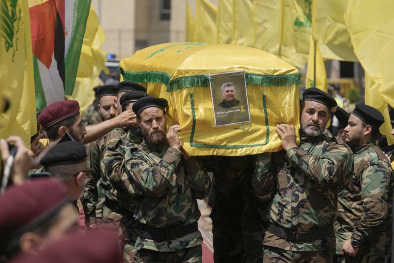 Hezbollah fighters carry the coffin of their comrade, senior commander Taleb Sami Abdullah, 55, known within Hezbollah as Hajj Abu Taleb, who was killed late Tusday by an Israeli strike in south Lebanon, during his funeral procession in the southern suburbs of Beirut, Lebanon, Wednesday, June 12, 2024. Hezbollah fired a massive barrage of rockets into northern Israel on Wednesday to avenge the killing of the top commander in the Lebanese militant group as the fate of an internationally-backed plan for a cease-fire in Gaza hung in the balance. (AP Photo/Bilal Hussein)