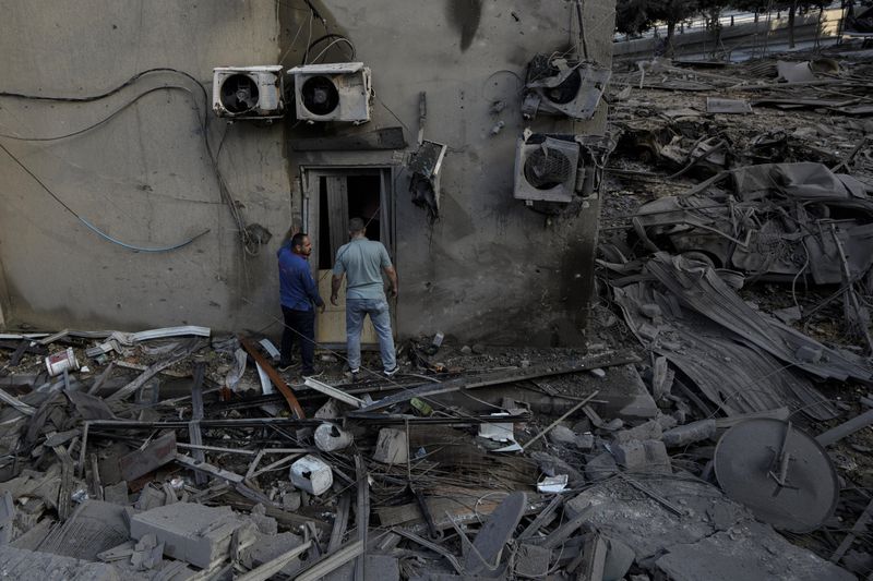 People check the site of an Israeli airstrike in Dahiyeh, Beirut, Lebanon, Sunday, Oct. 6, 2024. (AP Photo/Bilal Hussein)