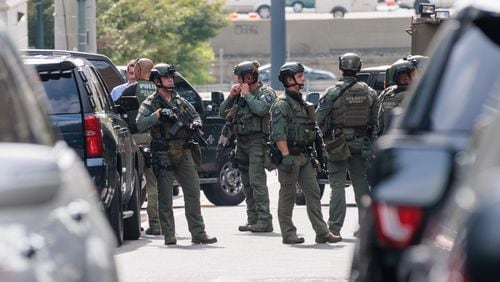 A SWAT team gathers outside a condominium building on 16th and Spring Street in Midtown Atlanta on Monday, August 22, 2022. A woman was arrested at the Atlanta airport a little more than two hours after shots were fired at the building, according to Atlanta police.The woman is suspected of shooting three people. (Arvin Temkar / arvin.temkar@ajc.com)