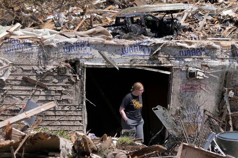 A woman walks out of the basement of a tornado damaged home, Wednesday, May 22, 2024, in Greenfield, Iowa. (AP Photo/Charlie Neibergall)