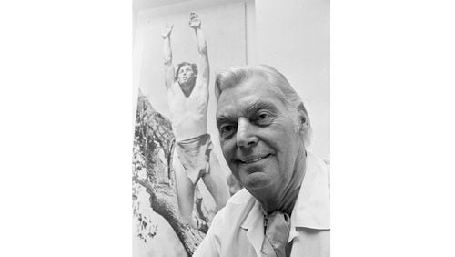 FILE - Olympic hero and film actor Johnny Weissmuller is pictured in front of a photo of himself as Tarzan, June 29, 1971. Weissmuller, who played Tarzan in the films was a swimming superstar in France 100 years ago. (AP Photo, File)