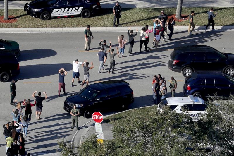 Students hold their hands in the air as they are evacuated by police from Marjory Stoneman Douglas High School in Parkland, Florida, after a shooter opened fire on the campus on Feb. 14, 2018. Seventeen students and staff were killed in the attack. (Mike Stocker/South Florida Sun-Sentinel via AP)