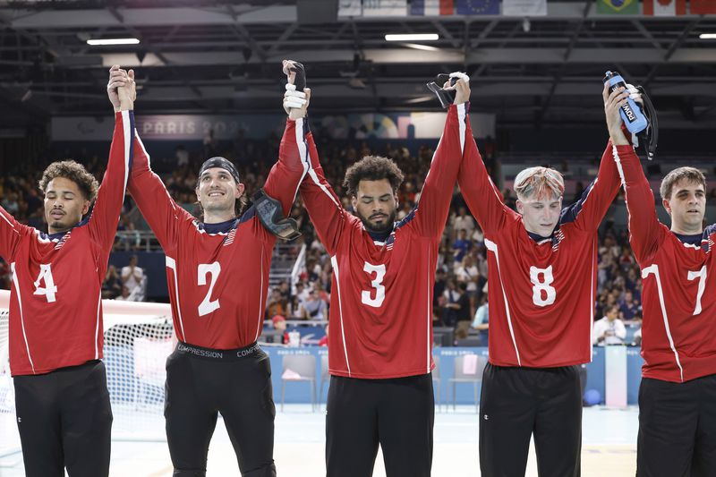 From left, U.S. team goalball players Tre'shaun Faison, Tyler Merren, Zion Walker, Christian King and Matt Simpson raise their hands after a 5-4 victory over the French men's goalball team during the Paralympic Games in Paris, Saturday, Aug. 31, 2024. (AP Photo/Felix Scheyer)