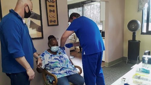 Anna Williams, a staff member at  Woodland Ridge Assisted Living getting morale support from Bear Mahon, the chief operating officer, as she gets her COVID-19 vaccine. She and 90 other residents and care providers opted for vaccines on Saturday.