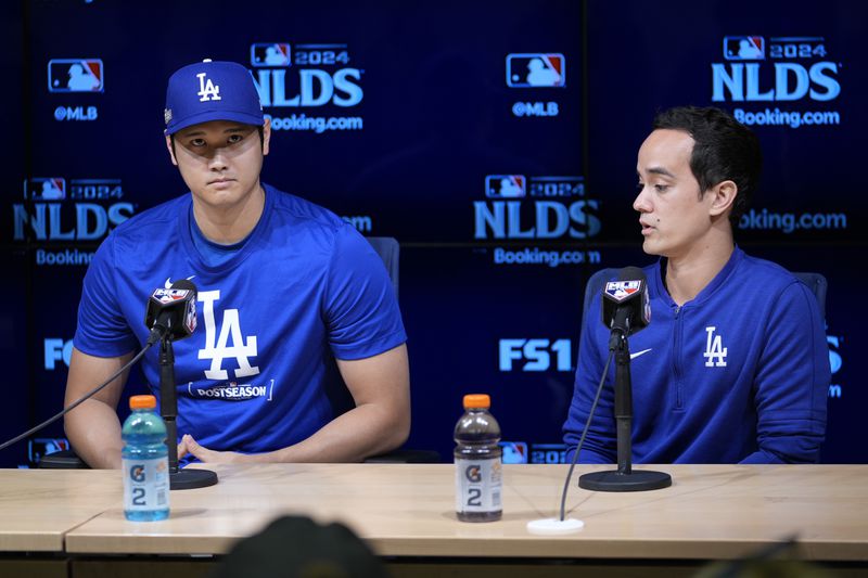 Los Angeles Dodgers' Shohei Ohtani, left, speaks to reporters with his interpreter, Will Ireton, in a press conference in preparation for Game 1 of a baseball NL Division Series against the San Diego Padres in Los Angeles, Friday, Oct. 4, 2024. (AP Photo/Ashley Landis)