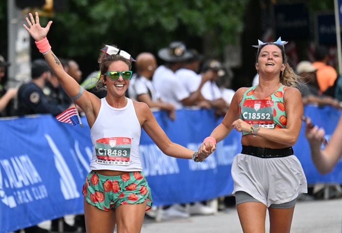 Amanda Connell (Left)  and Amanda Osprosky cross the finish line during the 55th Atlanta Journal-Constitution Peachtree Road Race in Atlanta on Thursday, July 4, 2024.   (Hyosub Shin / Hyosub.Shin / ajc.com)