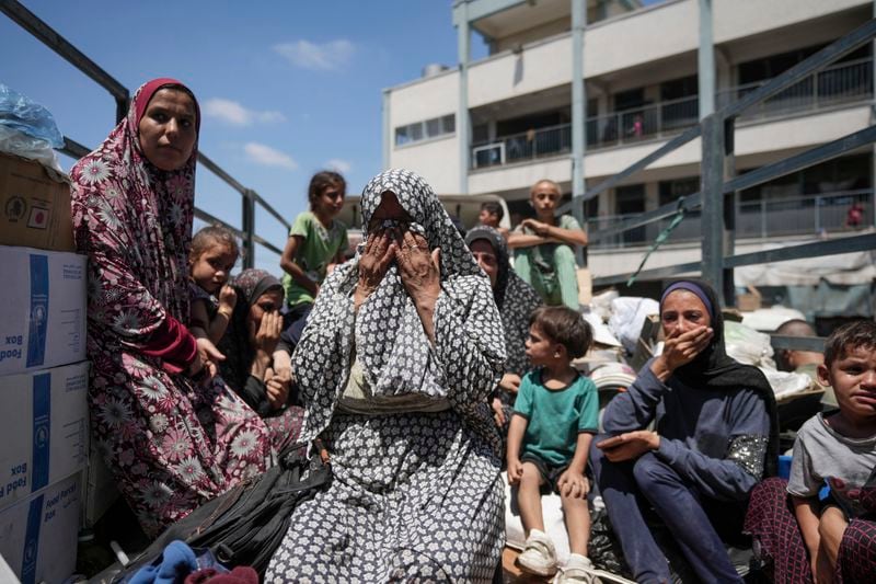 Palestinian women weep on a truck as she evacuates a school that had been her shelter, in eastern Deir al-Balah, Gaza Strip, Friday, Aug. 16, 2024, after the Israeli military dropped leaflets asking civilians to evacuate from the area, saying forces plan to respond to rocket fire that targeted Israel. (AP Photo/Abdel Kareem Hana)