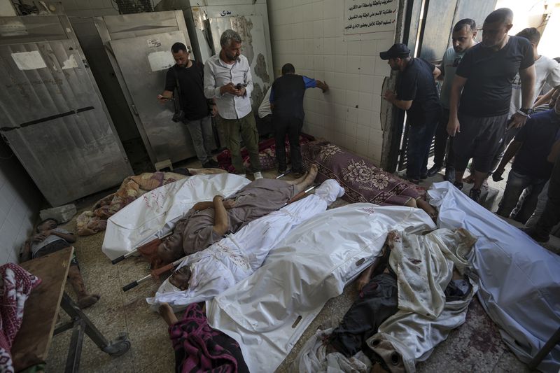 Palestinians check the bodies of their relatives killed in the Israeli bombardment of the Gaza Strip, at a hospital morgue in Deir al-Balah, Tuesday, Aug. 27, 2024. (AP Photo/Abdel Kareem Hana)