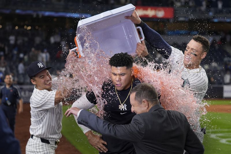 New York Yankees' Anthony Volpe, left, and Aaron Judge, right, dump a cooler on Juan Soto after he hit the game winning base hit during the tenth inning of a baseball game against the Boston Red Sox at Yankee Stadium Thursday, Sept. 12, 2024, in New York. The Yankees defeated the Red Sox 2-1. (AP Photo/Seth Wenig)