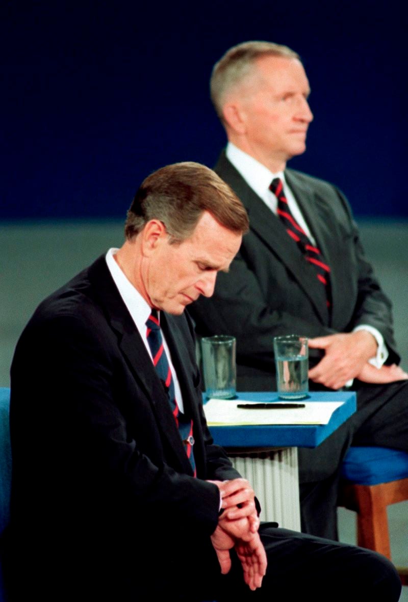 FILE - President George H.W. Bush looks at his watch during the 1992 presidential campaign debate with other candidates, Independent Ross Perot, top, and Democrat Bill Clinton, not shown, at the University of Richmond, Va., Oct. 15, 1992. (AP Photo/Ron Edmonds, File)