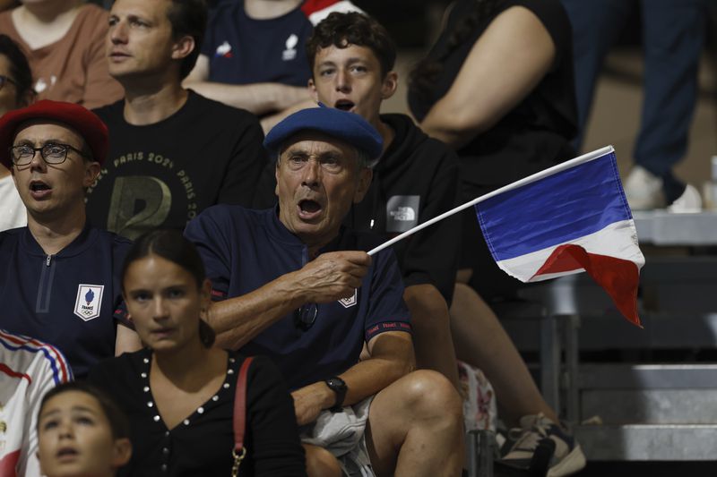 A fan waves a French flag while cheering during the mens' United States versus France goalball game during the Paralympic Games in Paris on Saturday, Aug. 31, 2024. Football fans are known for being loud and rowdy. But the Paralympic sports most closely related to football, blind football and goalball, require spectators to be silent during game action so that players can receive audible cues from the ball and the environment.(AP Photo/Felix Scheyer)