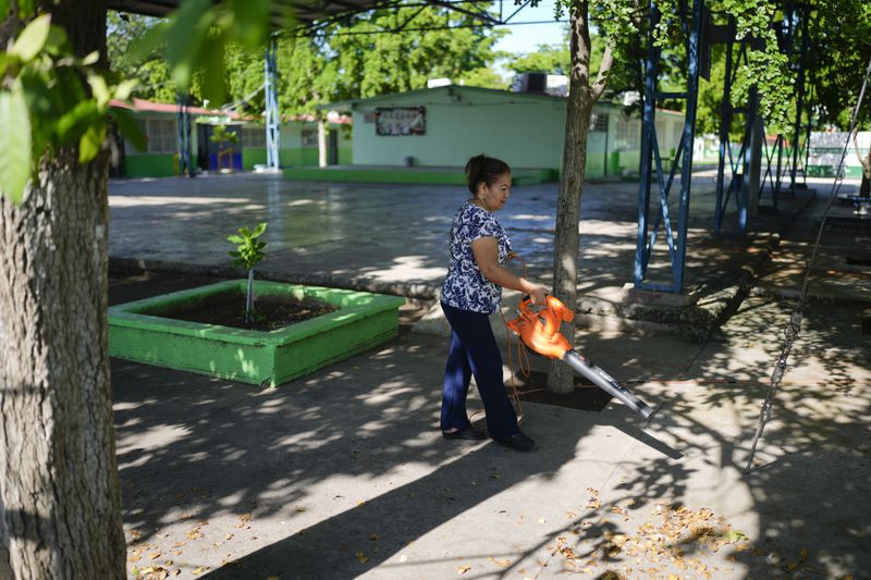 A person operates a leaf blower on the courtyard of the temporarily closed Lazaro Cardenas elementary school, in Culiacan, Sinaloa state, Mexico, Thursday, Sept. 19, 2024. (AP Photo/Eduardo Verdugo)