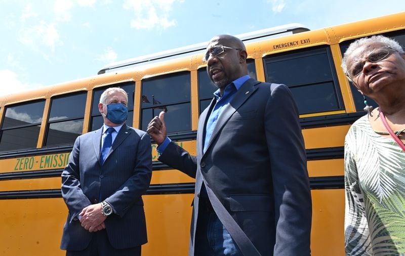 U.S. Sen. Raphael Warnock, D-Ga., speaks to members of the news media as Phil Horlock (left), President and CEO, looks after a test ride on an electric school bus at Blue Bird Corporation in Fort Valley May 4, 2021. (Hyosub Shin/The Atlanta Journal-Constitution)
