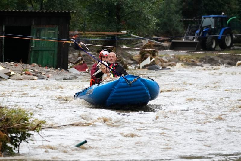 A resident with his dog is taken by a rubber boat from his flooded house in Jesenik, Czech Republic, Sunday, Sept. 15, 2024. (AP Photo/Petr David Josek)