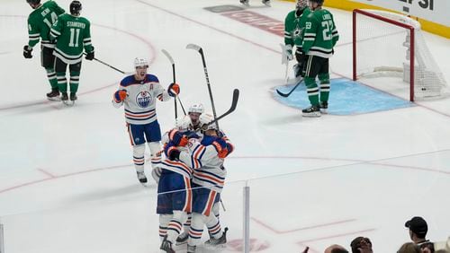 Edmonton Oilers players celebrate a game-winning goal by center Connor McDavid, bottom, left, during the second overtime in Game 1 of the NHL hockey Western Conference Stanley Cup playoff finals against the Dallas Stars, Thursday, May 23, 2024, in Dallas. (AP Photo/Tony Gutierrez)