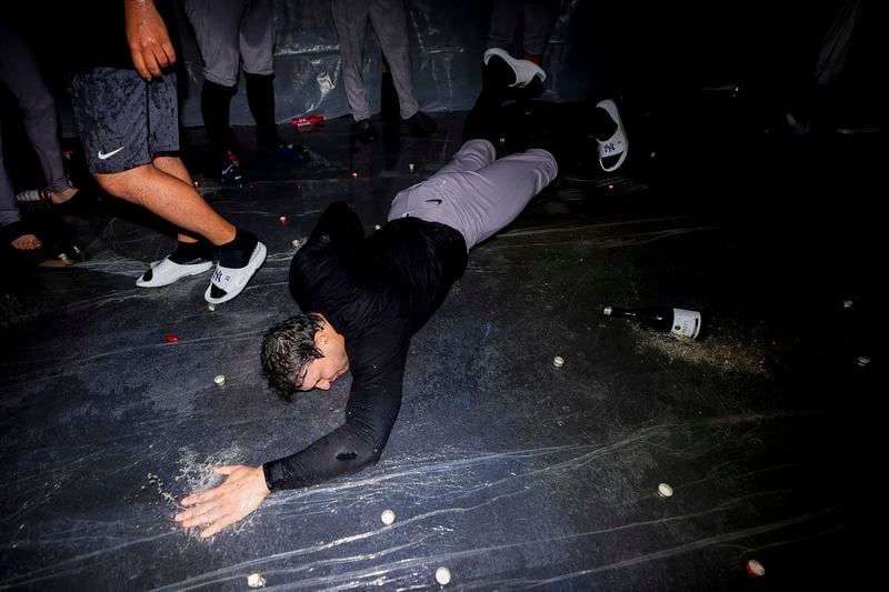 New York Yankees relief pitcher Tommy Kahnle slides on a layer of beer and champagne pooling on plastic in the visitor's clubhouse to celebrate clinching a playoff spot after a 2-1 win in 10 innings over the Seattle Mariners in a baseball game Wednesday, Sept. 18, 2024, in Seattle. (AP Photo/Lindsey Wasson)