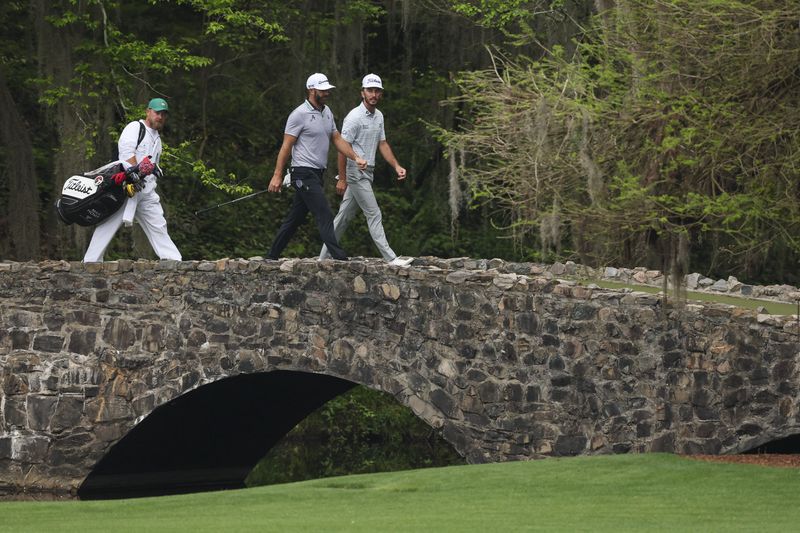 Dustin Johnson and Max Homa walk over the Nelson Bridge on the 13th hole.