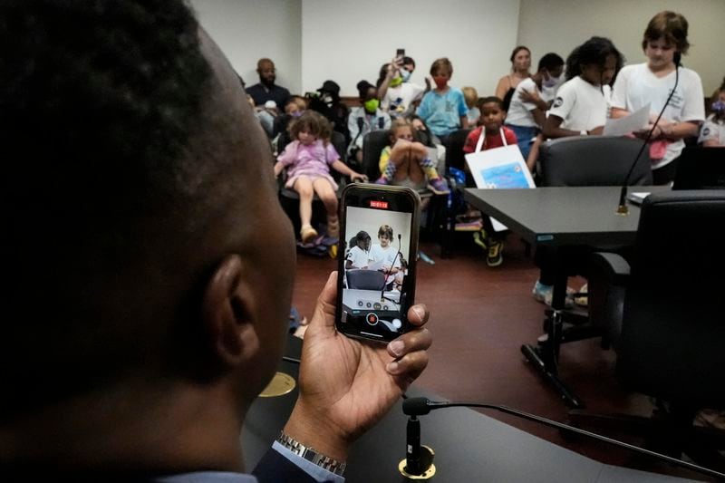 Georgia Rep. Derrick Jackson takes a photo of children speaking in a meeting at the state Capitol, where children spoke to legislators about gun violence, Thursday, Sept. 19, 2024, in Atlanta. (AP Photo/Mike Stewart)