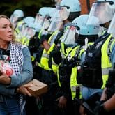 A woman carrying a baby doll walks in front of Riot control police Riot during a rally near the United Center, the site of the Democratic National Convention, on Thursday, August 22, 2024, in Chicago.
(Miguel Martinez / AJC)
