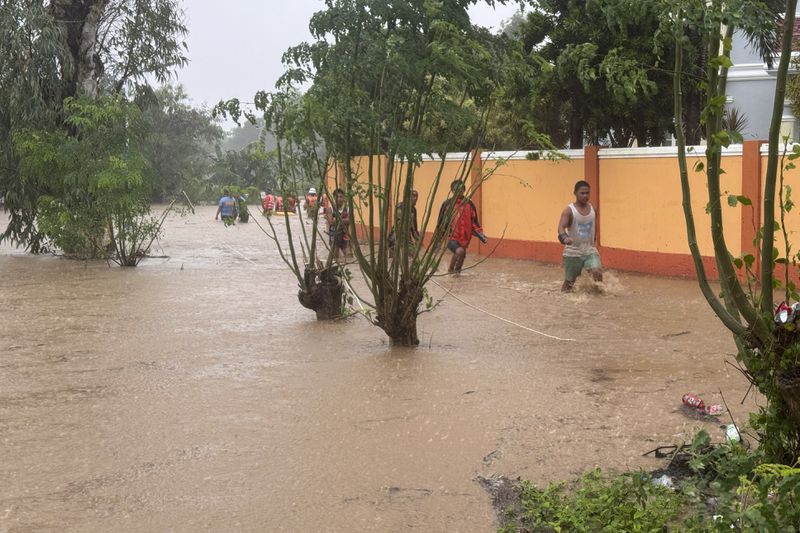 Residents negotiate floods caused by powerful Typhoon Krathon locally called "Typhoon Julian" at Bacarra, Ilocos Norte province, northern Philippines on Monday, Sept. 30, 2024. (AP Photo/Bernie Dela Cruz)