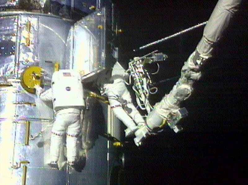 FILE - In this image from video provided by NASA, astronaut Claude Nicollier, left, maneuvers around the Hubble Space Telescope as astronaut Micheal Foale looks inside the observatory during a spacewalk Thursday, Dec. 23, 1999. (NASA via AP, File)