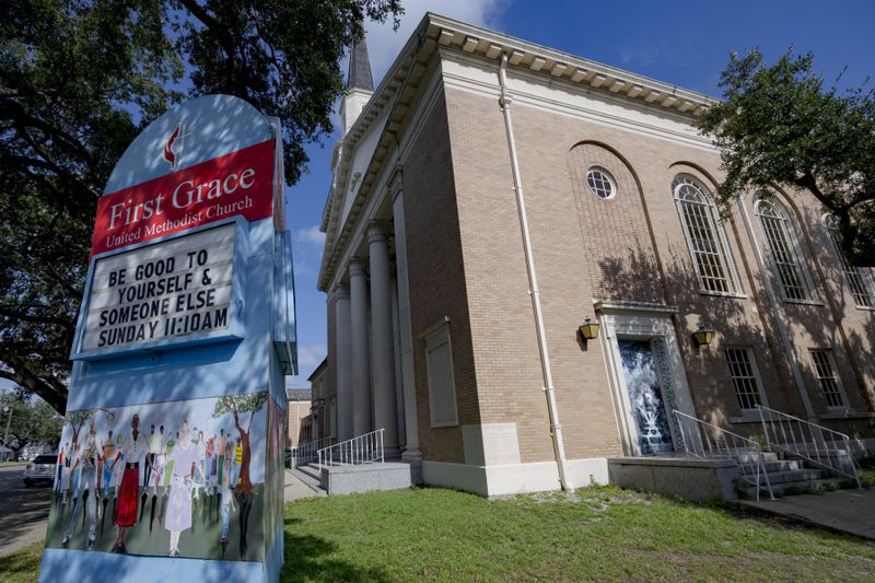 A sign for First Grace United Methodist Church, that is equipped with solar panels and Tesla batteries, is displayed in New Orleans, Wednesday, Sept. 25, 2024. The church is part of the Community Lighthouse initiative that uses microgrids, a small-scale power system that can operate and provide electricity amid hurricanes. (AP Photo/Matthew Hinton)