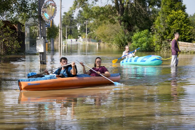 Residents paddle through a flooded street in Bohumin, Czech Republic, Tuesday, Sept. 17, 2024. (AP Photo/Darko Bandic)