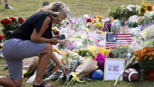 A mourner lays flowers at a makeshift memorial at the flagpole at Apalachee High School, Friday, Sept. 6, 2024, in Winder, Ga. A 14-year-old Apalachee High student is accused of shooting and killing two students and two teachers and injuring nine others at the school on Wednesday. (Jason Getz / AJC)