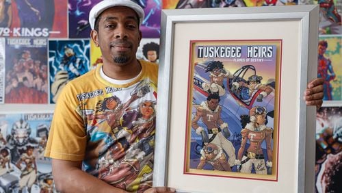 Marcus Williams, a visual comic artist poses with a framed poster of his comic book series Tuskegee Heirs at his home studio in Snellville on Wednesday, May 22, 2024. (Natrice Miller/ AJC)