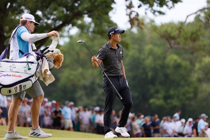 Collin Morikawa hands his club to his caddie after hitting his second shot on the 18th fairway during the final round of the Tour Championship at East Lake Golf Club on Sunday, Sept. 1, 2024, in Atlanta.
(Miguel Martinez / AJC)